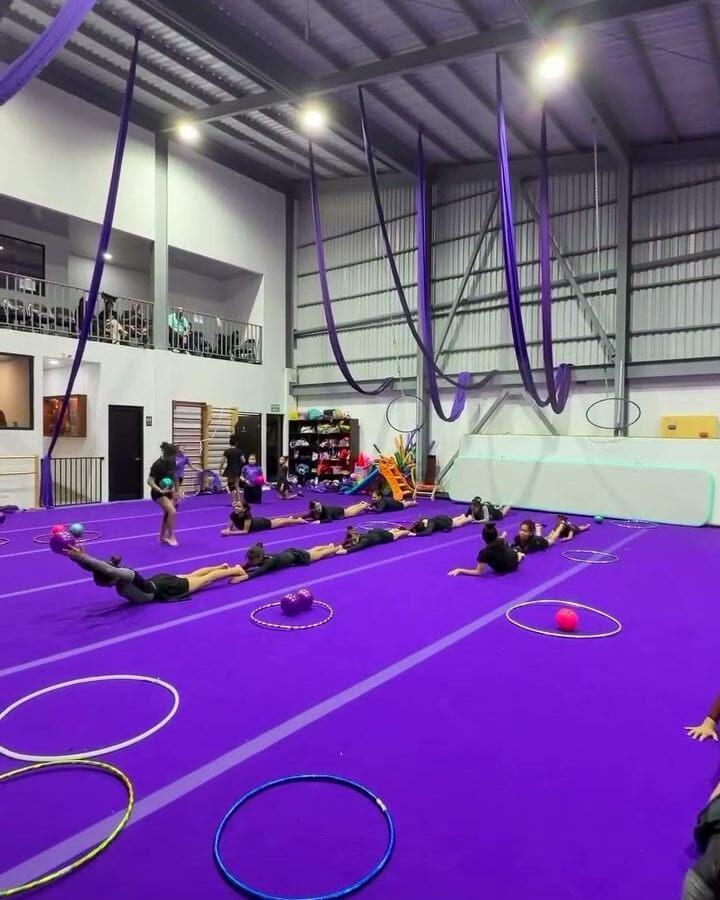 Clase de gimnasia rítmica sobre el piso violeta de AlilÚ Studio, con aros en el suelo