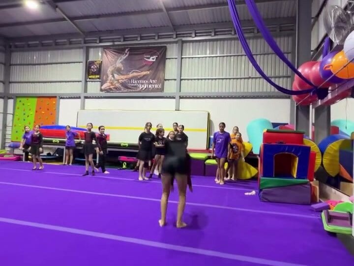 Grupo de atletas junto a la pista de tumbling durante el entrenamiento