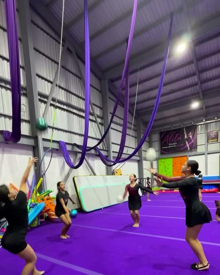 Telas aéreas violetas colgando de la estructura del gimnasio de AlilÚ Studio
